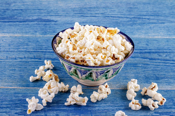 Popcorn in a ceramic bowl on a blue wooden background