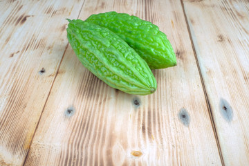 Fresh bitter melon or bitter gourd (Momordica charantia)  over pine wood grain
