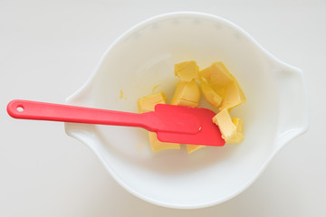 Butter in mixing bowl with silicone spatula