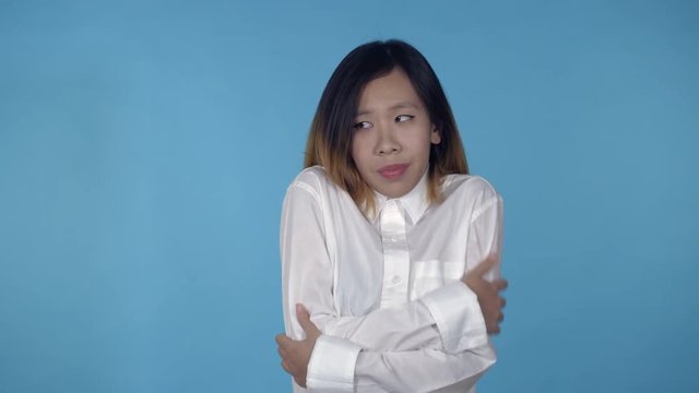 young asian woman posing freezes on blue background in studio. attractive millennial girl wearing white casual shirt looking at the camera