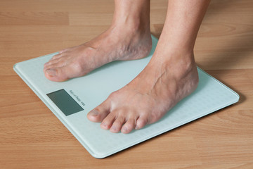 Legs of a young woman on a digital scale. Checking the weight. The concept of weight loss.