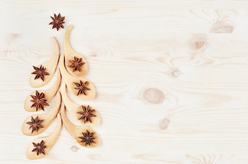 Funny christmas tree of bamboo spoons with anise stars on white wood background.