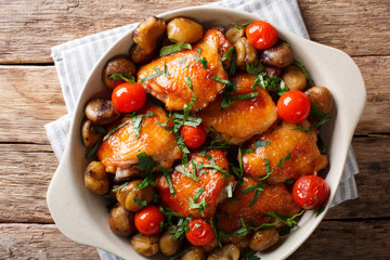 Fried chicken with chestnuts, greens and tomatoes close-up in a bowl. Horizontal top view
