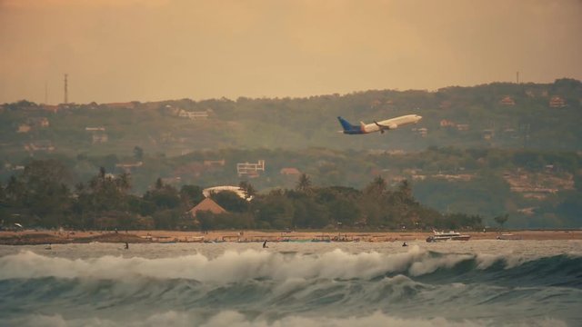 plane takes off over the waves of the ocean at sunset in slow motion