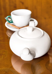 White teapot and empty tea cup on the table.