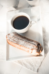 Chocolate eclair on the plate and cup of coffee