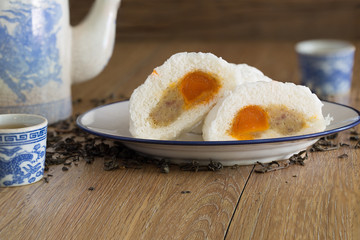 Steam Buns (Sa La Pao) stuffed pork chop and salted egg, Chinese snack with Chinese pot tea on wooden background