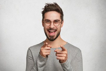 Hey you! Portrait of fashionable hipster guy has trendy hairdo, points with fore fingers at you,...
