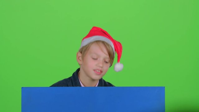 Child boy out of hiding from behind a blue poster on a green screen