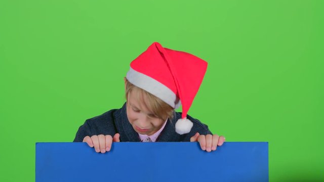 Teen in cap emerges from behind the board on a green screen