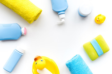 Bath accessories for kids. Yellow rubber duck, soap, sponge, brushes, towel on white background top view copyspace