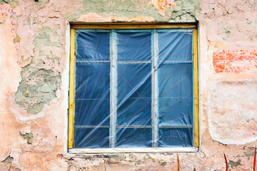 Old window with plastic membrane instead of glass