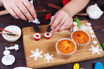 Making Santa's boots cupcake decoration of confectionery mastic, close up. Family culinary and New...