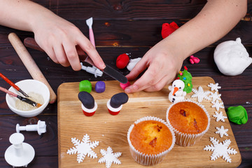 Obraz na płótnie Canvas Process of making Santa's boots cupcake decoration of confectionery mastic, close up. Family culinary and New Year traditions concept, festive food, party treats, cooking