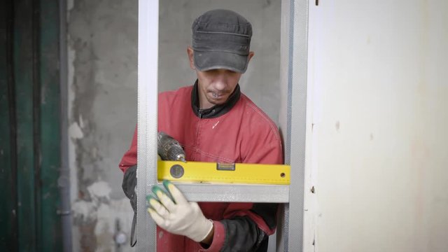 Professional constructor using leveling gauge for measuring on building site
