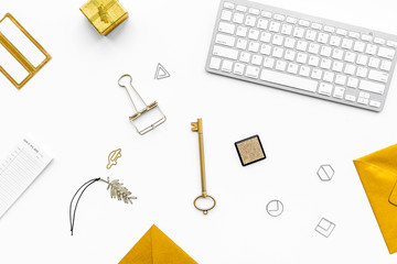 Fashoin in the workplace. Office desk in a trendy gold color. Stationery near keyboard on white background top view
