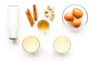 Ingredients for eggnog. Eggs, milk, cinnamon, whiskey on white background top view