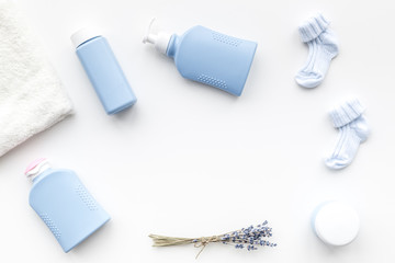 Natural bath cosmetics for kids. Bottles, booties and towel on white background top view copyspace