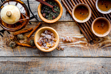 Obraz na płótnie Canvas Tea ceremony concept. Tea pot, cups, dry tea leaves, sugar on rustic wooden background top view copyspace