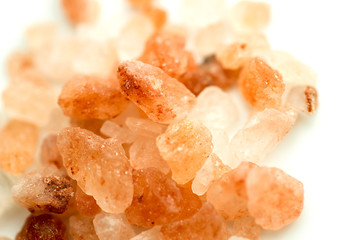 Himalayan rose and orange salt crystals piled and isolated on white background