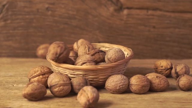 Wallnuts falling into the bowl on the old wooden table