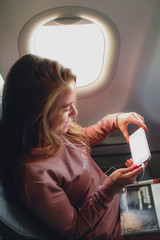 Girl is reading from smartphone in airplane near window