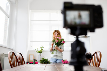 Picture of young woman florist composing bouquet of pink flowers.
