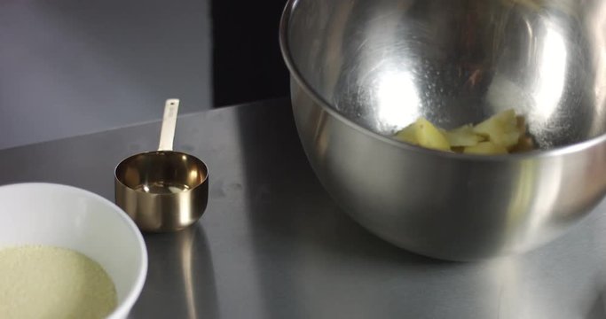 Male chef preparing potato casserole with cheese and olive oil in a large stainless steel bowl
