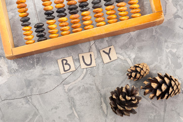 Word BUY laid out of handwritten letters on cardboard squares near old wooden abacus and three...