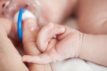 Hand the sleeping baby in the hand of mother close-up.