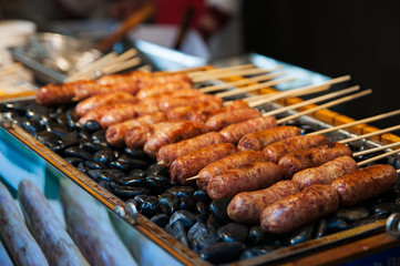 Grilled sausages. Closeup of sausage prepared on stones at China market. Chinese street food