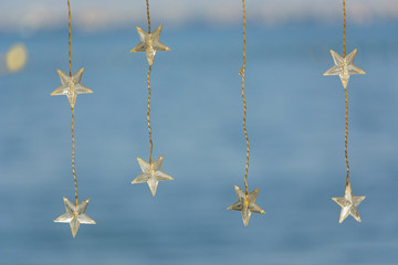 Decorative bohemian LED light wires with stars hanging on bright blue beach and blurred background