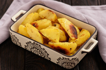 Baked potatoes with garlic and spices on wooden background.