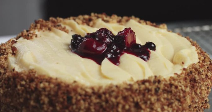 Adding forest berries compote to the top of a custard cream sponge cake, close up video