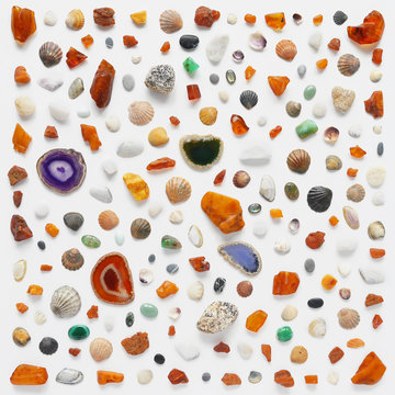 A creative pattern of shells, cones, unprocessed pieces of amber, natural stones, starfish. Composition of natural materials, flat lay, top view. Summer, sea concept. Marine background, stone texture.