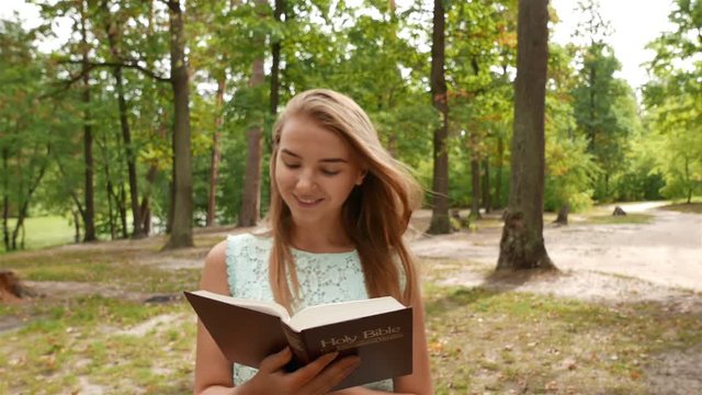4k.Young modern girl  walk with Bible in park. Christian team shot