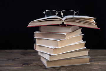 Heap of books and glasses. A lot of books for studying on a black background. Education