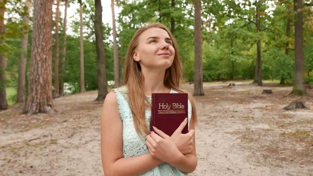 4k.Young  girl  with Bible in park. Christian team  steady shot