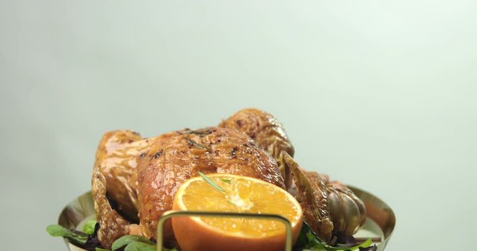 Ready browned roasted chicken with oranges and rosemary painted with olive oil before servind isolated on white