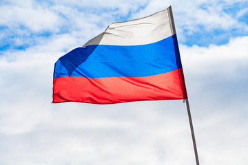Flag of the Russian Federation fluttering in the wind a background of blue sky and clouds