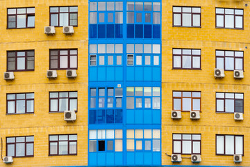 Yellow and blue facade of a modern residential building with air conditioning  (background, texture)