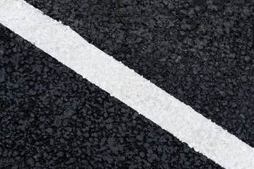 Fototapeta premium White diagonal marking line on the asphalt road (background, texture, abstract)