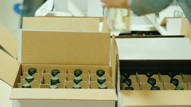 Packing of finished products in the winery. Bottles with white wine are put in cardboard boxes