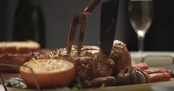 Close up video of carving homemade roasted chicken with oranges and rosemary on a Christmas party table