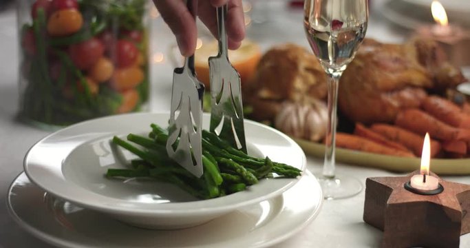 Serving steamed vegetables and roasted chicken on white round porcelain plates during a Christmas party