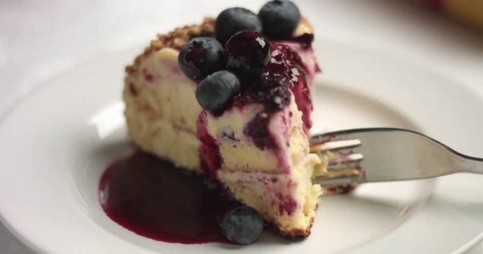 Pouring blueberry syrup on a slice of homemade sponge cake with custard and fruit berries confiture and fresh blueberries