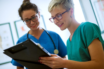 Close up view of two professional nurses with eyeglasses checking the patient papers in a doctors...