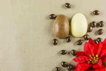 Easter - Brown and white chocolate eggs and a red flower.