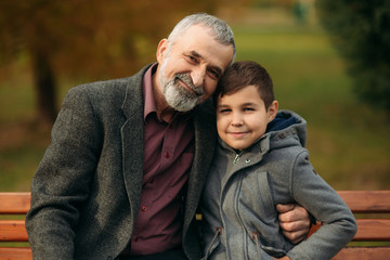 Grandpa and his grandson spend time together in the park. They are sitting on the bench. Walking in the park and rejoicing