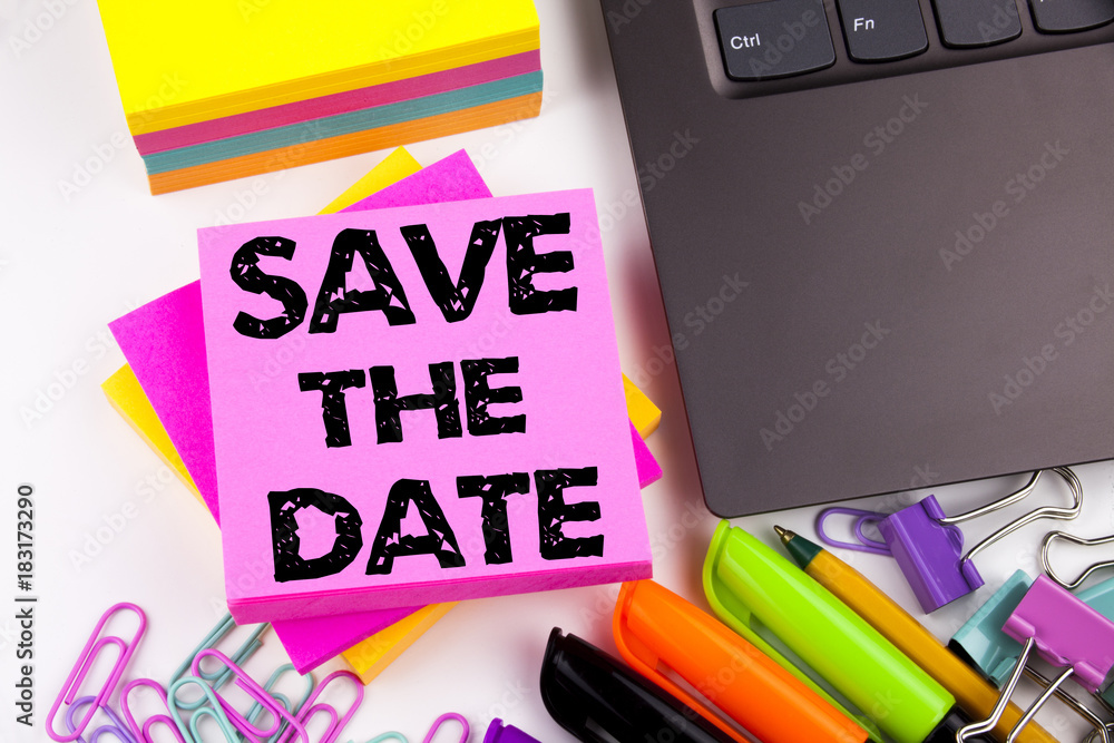 Poster writing text showing save the date made in the office with surroundings such as laptop, marker, pen.